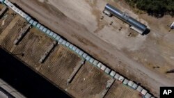 En la imagen aérea se observan baños portátiles en un área que fue usada por migrantes, muchos de Haití, en un campamento a lo largo del Puente Internacional Del Río, Texas, el 24 de septiembre de 2021.