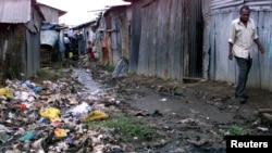 Un homme marche en évitant les égouts et les ordures dans le bidonville appauvri de Kibera, à quatre kilomètres de Nairobi, le 28 juin 2002. (Photo: Reuters)