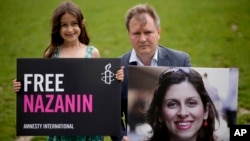 FILE - Richard Ratcliffe, the husband of imprisoned British-Iranian Nazanin Zaghari-Ratcliffe and their seven year-old daughter Gabriella pose for the media with a photo of her, in London, Britain, Sept. 23, 2021. 