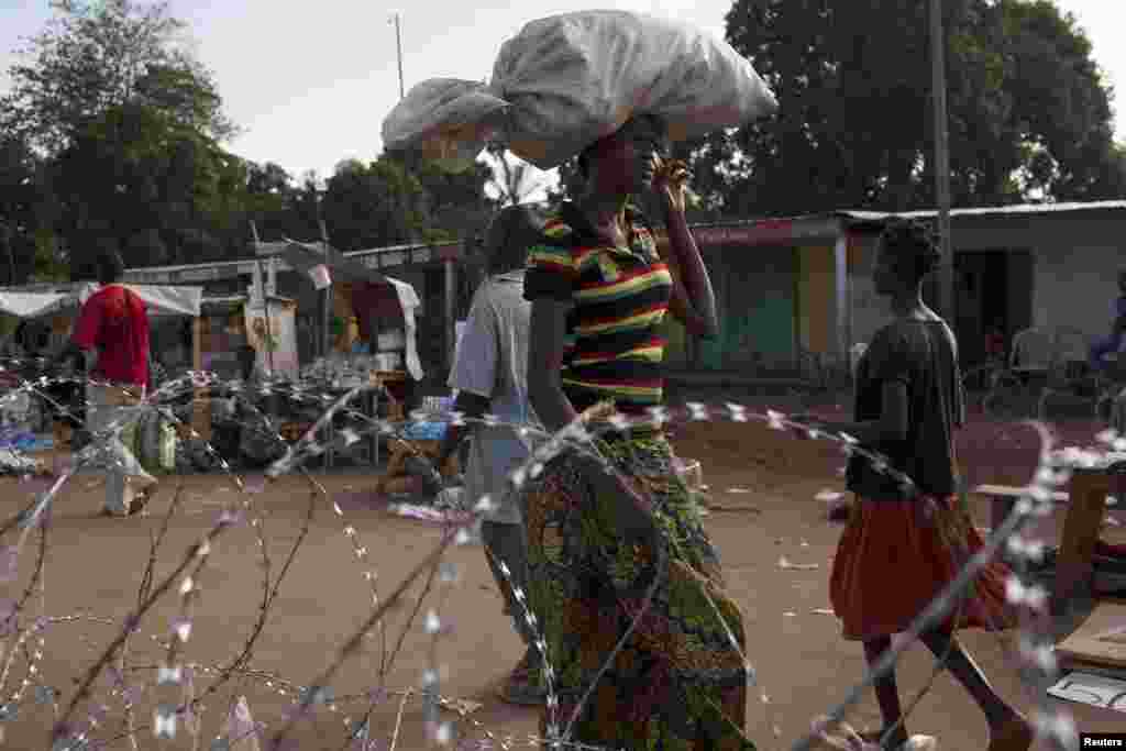 A woman carrying a load on her head approaches a security checkpoint at Kilometre 12 in Bangui, March 3, 2014.