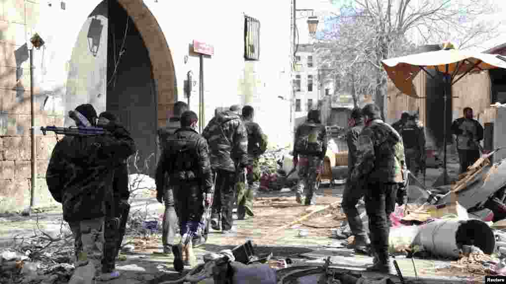 Forces loyal to Syria's President Bashar al-Assad carry their weapons as they walk along a street in the old city of Aleppo, Feb. 10, 2014.