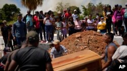 Los residentes colocan el ataúd que contiene los restos del minero Richard Bastardo, en una tumba en el cementerio de La Paragua, estado Bolívar, Venezuela, el jueves 22 de febrero de 2024. (Foto AP/Ariana Cubillos)