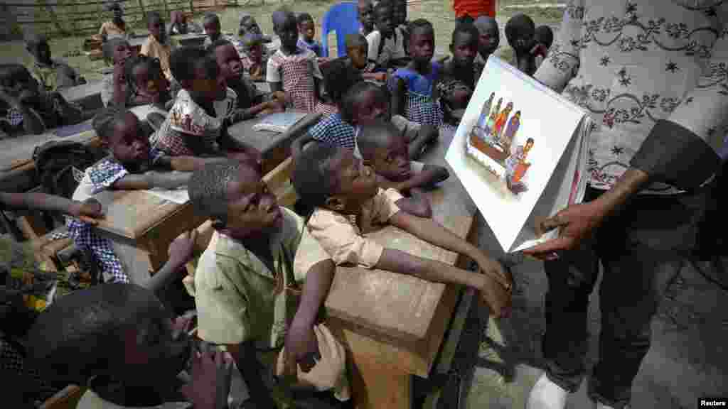 A man shows a picture to students during a United Nations Children's Fund (UNICEF) Ebola awareness drive in Gueupleu, Man, western Ivory Coast, Nov. 3, 2014.