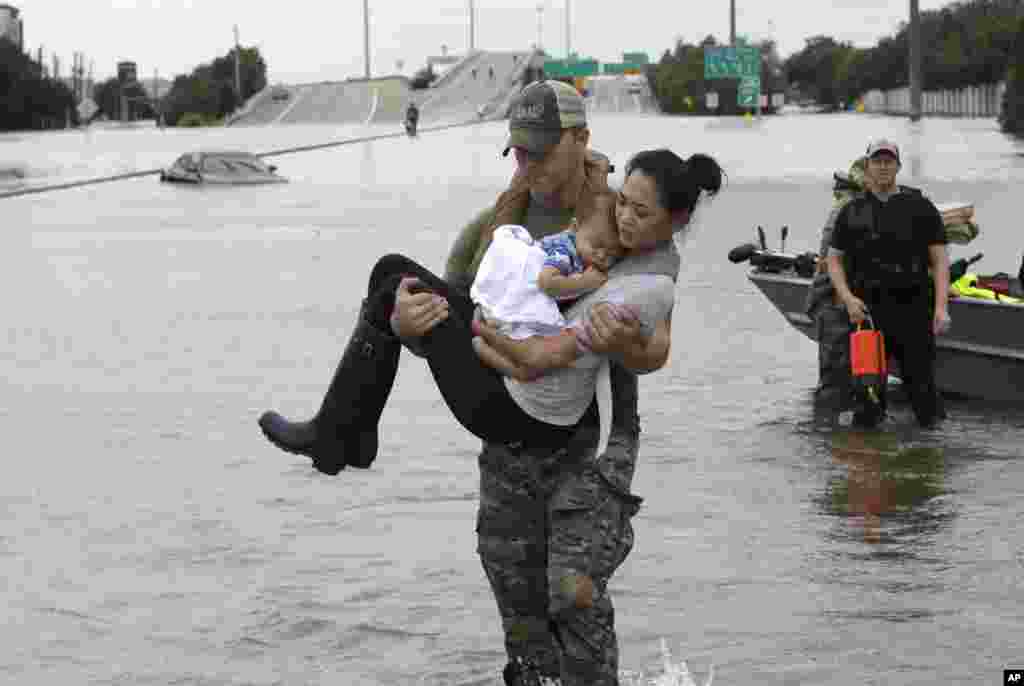 Houston Police SWAT officer Daryl Hudeck carries Catherine Pham and her 13-month-old son Aiden after rescuing them from their home surrounded by floodwaters from Tropical Storm Harvey, Aug. 27, 2017, in Houston.