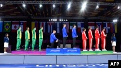 El esgrimista estadounidense Race Imboden se arrodilla durante el himno nacional en la ceremonia de entrega de medallas del Equipo de florete masculino en Esgrima, durante los Juegos Panamericanos de Lima, Perú, el 9 de agosto de 2019. 