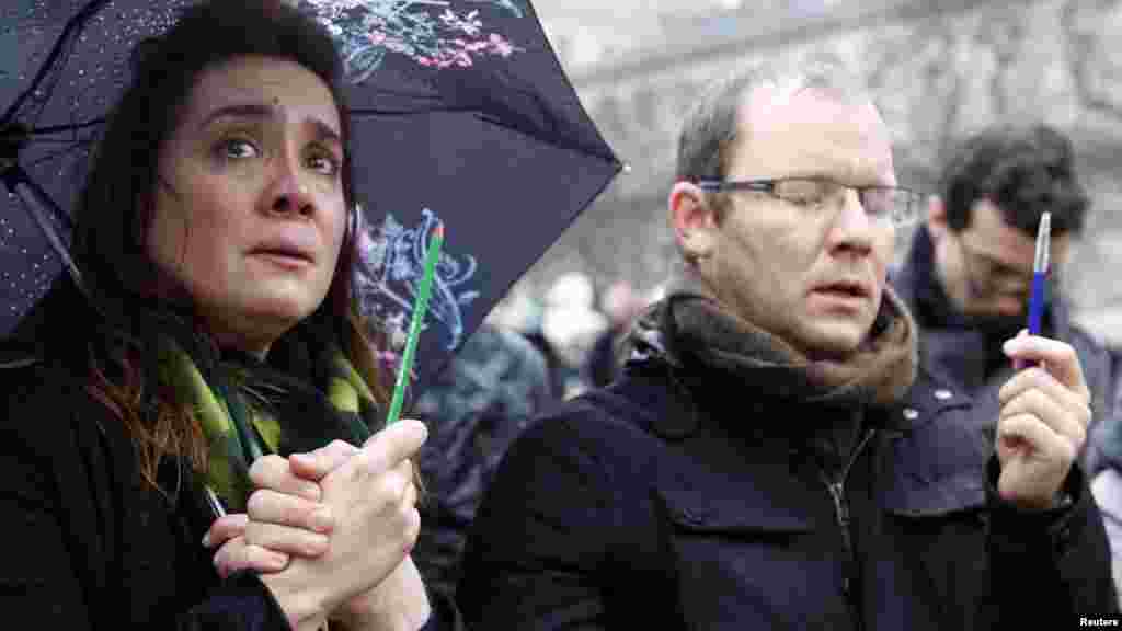 Une femme tenant un crayon pleure lors d'un rassemblement en face de la cathédrale Notre-Dame pendant la minute de silence pour les victimes de la fusillade mercredi dans les bureaux Charlie Hebdo, à Paris, le 8 janvier 2015.ris, Jan. 8, 2015.