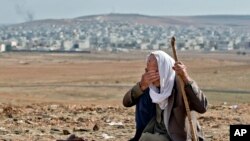 Pengungsi Kurdi Suriah, Mohammad Hassan, 84 tahun, dari Kobani menangis, dengan latar belakang kampung halamannya, di bukit pinggiran Suruc, Turki, dekat perbatasan Turki-Suriah, Minggu, 26 Oktober 2014. 