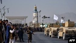 Orang-orang menonton parade militer Taliban unit Al-Badr di Kandahar pada 8 November 2021 sebagai ilustrasi. ISIS mengaku bertanggung jawab atas pengeboman di dekat pos pemeriksaan di bandara militer Ibu Kota Afghanistan.(Foto: AFP/Javed TANVEER)