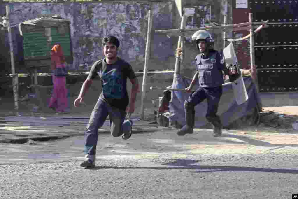 A riot police officer chases a garment worker during clashes in Ashulia on the outskirts of Dhaka, Bangladesh, Nov. 12, 2013.