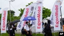 ARCHIVO - Estudiantes de secundaria pasan junto a banderas de ExxonMobil en la Universidad de Guyana en Georgetown, Guyana, el 21 de abril de 2023. (Foto AP/Matías Delacroix, Archivo)