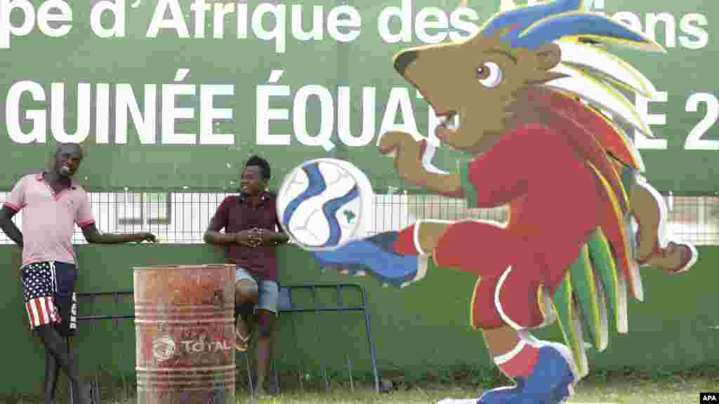 Des hommes non identifiés sont debout devant un kioske de vente de billets avant le match d'ouverture du groupe A de la Coupe d'Afrique des Nations de football à Bata, en Guinée équatoriale, le vendredi 16 janvier 2015.