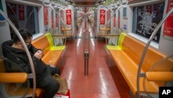 A man wearing a face mask rides a nearly empty subway train in Beijing, China.