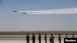 中國空軍兩架殲-11戰機飛越遼寧瀋陽一個機場上站立的中國士兵們。（2019年4月3日）