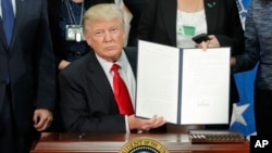Le président américain Donald Trump montre le décret sur la sécurité aux frontières et l’immigration après l’avoir signé à Washington, 25 janvier 2017.