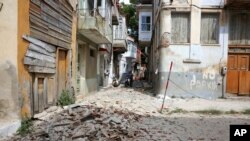 Warga memandang reruntuhan dari gedung yang rusak setelah terjadinya sebuah gempa bumi di desa Plomari di timur laut Pulau Lesbos, Yunani, hari Senin, 12 Juni 2017 (foto: Manolis Lagoutaris/InTime News via AP)