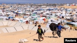 Los niños pasean con un perro, mientras los palestinos desplazados debido a los ataques israelíes, se refugian en un campamento en la frontera con Egipto, en Rafah, al sur de la Franja de Gaza, 8 de febrero de 2024.