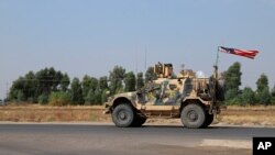 FILE - A U.S. military vehicle, part of a convoy, arrives near Dahuk, Iraqi, Oct. 21, 2019.