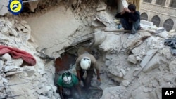 Civil Defense workers from the White Helmets dig in the rubble to remove bodies and look for survivors after airstrikes hit the Bustan al-Basha neighborhood in Aleppo, in this photo provided by the Syrian Civil Defense group.