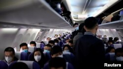 上海虹橋國際機場乘坐一架上海航班的旅客都戴著口罩防止感染新冠病毒。（2020年3月25日）