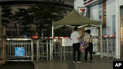 Dos personas observan a la entrada de un centro deportivo donde un hombre embistió contra gente que hacía ejercicio en Zhuhai, China, el lunes 11 de noviembre de 2024. 