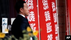 一名男子走过东京日本自民党总部竖立的竞选总裁的旗帜。（2024年9月12日）