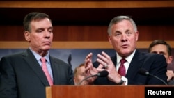 El presidente del Comité de Inteligencia del Senado Richard Burr (R-NC), a la derecha, y el vicepresidente del comité, el senador Mark Warner (D-VA) hablan con los medios en el Capitolio sobre los hallazgos y recomendaciones del comité sobre amenazas a la infraestructura electoral. Marzo 20 de 2018.