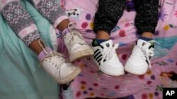 Dos hermanos de 7 y 3 años sentados juntos en una cama en la casa a la que la familia se mudó en octubre de 2023, cinco años después de huir de Venezuela a Colombia. La familia fue entre los primeros migrantes que ingresaron a EEUU bajo las "oficinas de movilidad segura".