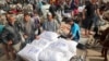 Ljudi pune svoja kolica vrećama brašna u distributivnom centru UNRWA u Deir el-Balahu u centralnom pojasu Gaze, 3. novembar, 2024.(Foto: AFP /Eyad BABA)
