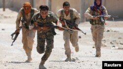 Des combattants kurdes des Unités de protection du peuple (YPG) en action dans une rue de Raqqa, en Syrie, le 3 juillet 2017.
