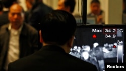 An airport security personnel looks at the screen showing body temperatures scan of arriving travellers at Hong Kong International Airport, Apr. 9,2013.