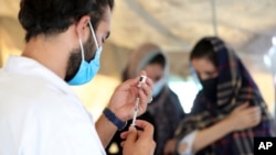 FILE - A doctor fills a syringe with the Johnson & Johnson COVID-19 vaccine at a vaccination center, in Kabul, Afghanistan, July 11, 2021.