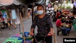 អាជីវករម្នាក់ដែលមានពាក់ម៉ាស់ ធាក់កង់ធ្វើអាជីកម្មនៅក្នុងផ្សារមួយ ក្នុងអំឡុងពេលរាតត្បាតនៃជំងឺកូវីដ១៩ នៅក្រុងម៉ានីល ប្រទេសហ្វីលីពីន កាលពីថ្ងៃទី ១២ ខែមីនា ឆ្នាំ២០២១។