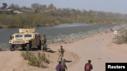 Un grupo de migrantes de Venezuela camina a lo largo de las orillas del Río Grande para entregarse a la Patrulla Fronteriza de EEUU después de ingresar a Texas en Eagle Pass, Texas, el 8 de enero de 2024.