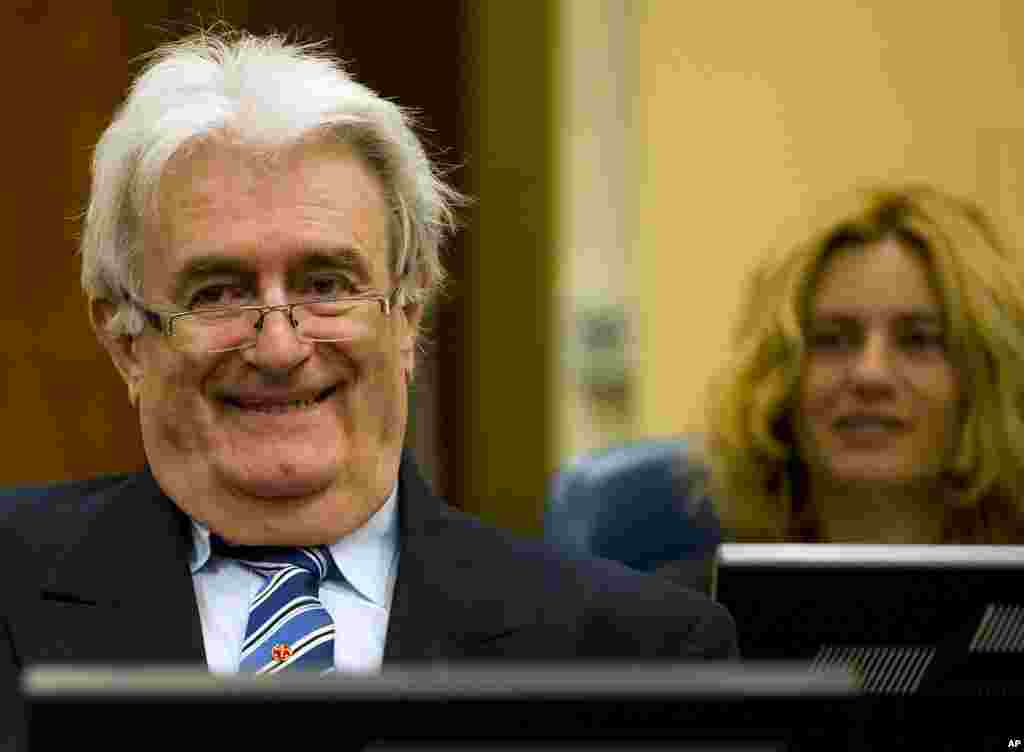 Suspected war criminal and former Bosnian Serb leader Radovan Karadzic smiles as he takes his seat on the defense bench in a courtroom to start his defense at the U.N. war crimes tribunal in The Hague, Netherlands, Oct. 16, 2012.