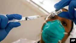 La doctora Yomaris Peña, del centro de salud Somos Cummunity Care, extrae los últimos residuos de un frasco de la vacuna de Pfizer/BioNTech en enero pasado.