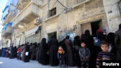 FILE - Women and children queue to receive free meals in Aleppo, Syria, Feb. 2, 2017. 