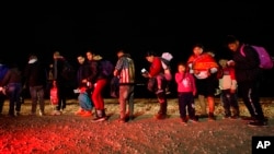 FILE - Migrants wait to be processed after crossing the U.S. border. Jan. 6, 2023, near Yuma, Ariz.