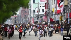 Pekerja garmen Bangladesh melemparkan berbagai benda ke arah petugas keamanan. Sekitar 15.000 pekerja memblokir berbagai jalan utama di Dhaka, sebagai bagian dari aksi protes atas upah rendah dan kondisi kerja yang memprihatinkan.