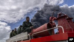 Los bomberos se desplazan en un camión dentro de la base de superpetroleros de Matanzas para sofocar un incendio que comenzó durante una tormenta eléctrica, en Matanzas, Cuba, el domingo 7 de agosto de 2022.