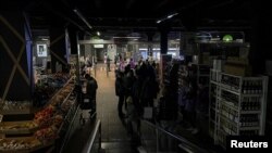 Los residentes de un barrio de Kiev visitan un supermercado completamente a oscuras tras los ataques rusos que ha dejado sin suministro eléctrico a miles de personas.