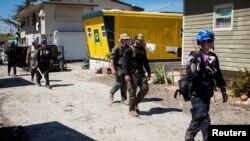 Trabajadores de la Administración Federal de Manejo de Emergencias (FEMA)caminan por áreas afectadas por el huracán Ian en Fort Myers, Florida, el 3 de octubre de 2022.