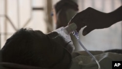 ARCHIVO - Un pariente ajusta la máscara de oxígeno de un paciente con tuberculosis en un hospital de TB en el Día Mundial de la Tuberculosis en Hyderabad, India, el 24 de marzo de 2018.