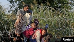 Des migrants syriens et la clôture barbelée à la frontière entre la Hongrie et la Serbie, près deRöszke, le 27 août 2015. (REUTERS/Bernardett Szabo - RTX1XX6V)