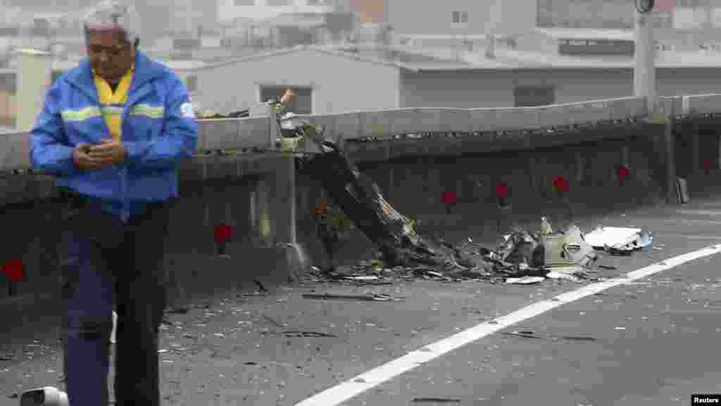 Un homme marche près de débris de l'avion de TransAsia Airways qui s'est abimé dans une rivière juste après son décollage dans la nouvelle ville Taipei.
