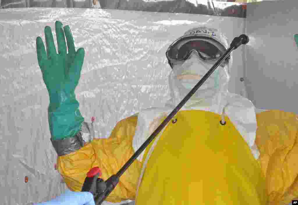 A health worker is sprayed with disinfectant after he worked with patients infected with the Ebola virus, at a clinic in Monrovia, Liberia, Sept. 8, 2014. 