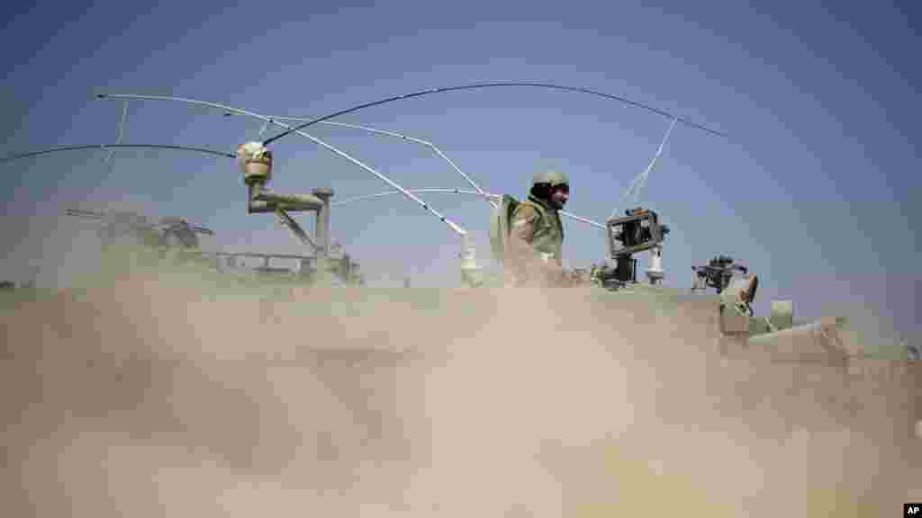 Israeli soldiers drive on an armored personal carrier near the Israel and Gaza Strip border, July 7, 2014.