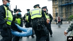 Police detain a man, during a coronavirus anti-lockdown protest on Westminster Bridge, in London, Saturday, Oct. 24, 2020. (AP Photo/Alberto Pezzali)