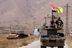 FILE - Hezbollah and Syrian flags flutter on a military vehicle in Western Qalamoun, Syria, Aug. 28, 2017.