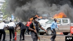 Des personnes éteignent un incendie causé par l'explosion d'une bombe près du bâtiment du Parlement à Kampala, en Ouganda, le 16 novembre 2021.