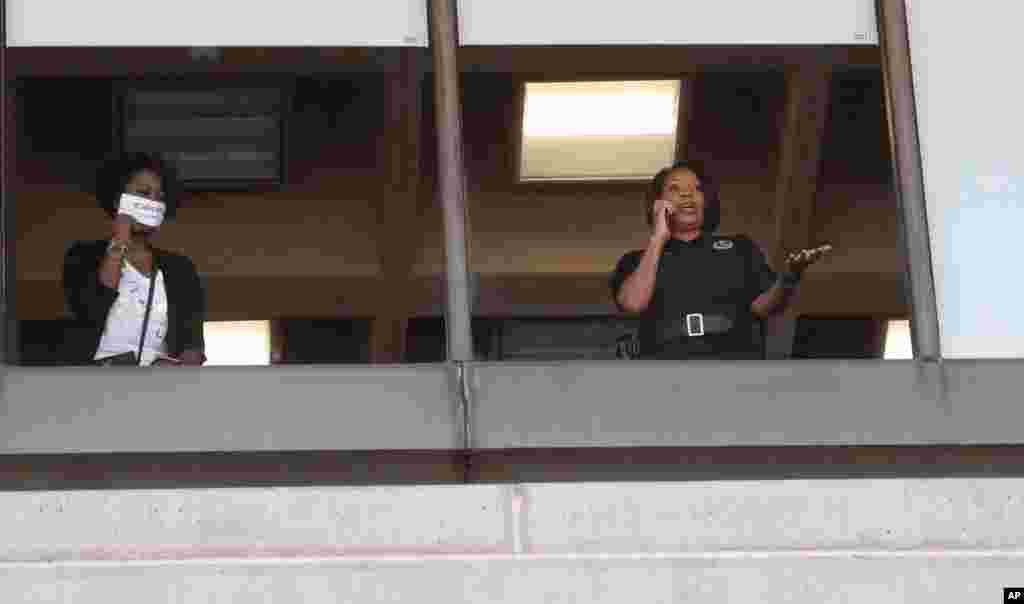 La jefa de la policía de Dallas, Renee Hall, a la derecha, mira desde una ventana mientras los manifestantes se reúnen frente al Ayuntamiento de Dallas, el sábado.